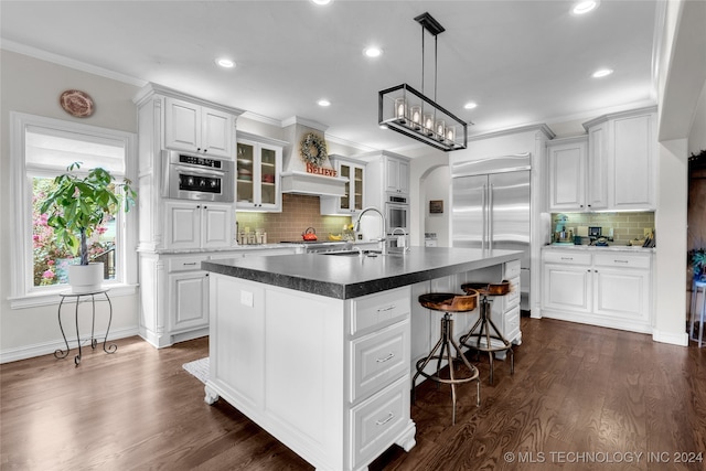 kitchen with an island with sink, white cabinets, and sink