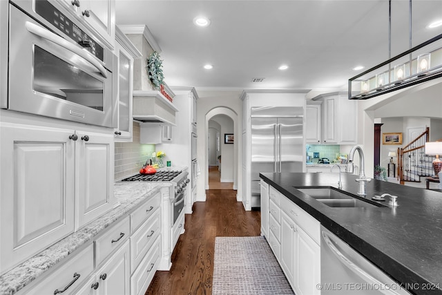 kitchen with dark wood-type flooring, sink, high end appliances, white cabinetry, and decorative backsplash