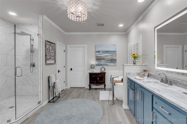 bathroom with an inviting chandelier, hardwood / wood-style floors, separate shower and tub, ornamental molding, and vanity