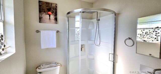 bathroom with a shower with door and toilet