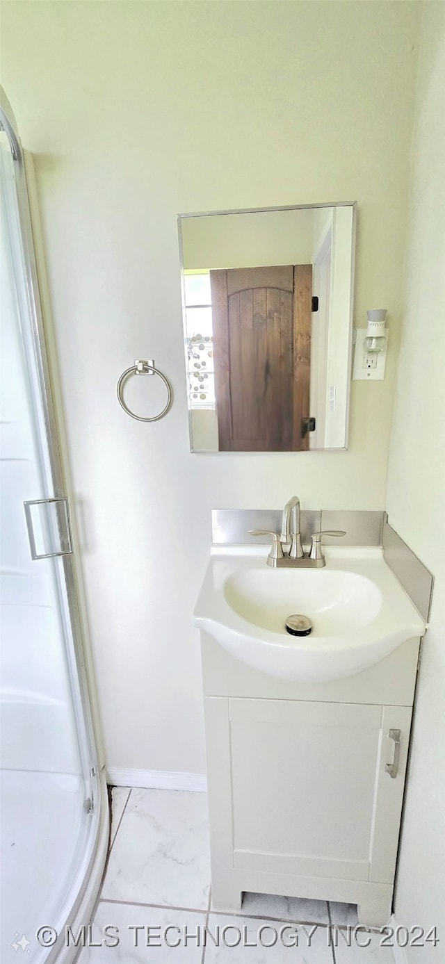 bathroom featuring a shower with shower door and vanity