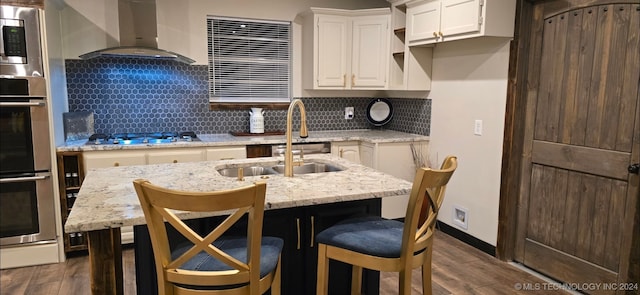 kitchen with light stone countertops, appliances with stainless steel finishes, wall chimney exhaust hood, and dark hardwood / wood-style floors