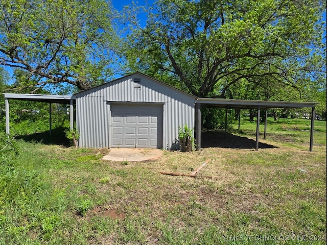 view of outdoor structure with a garage, a carport, and a yard