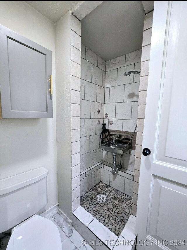 bathroom featuring tiled shower and toilet