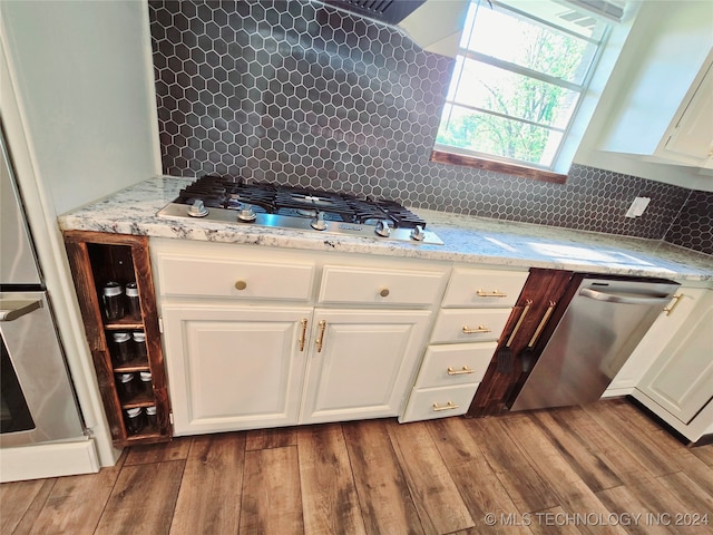 kitchen featuring light wood-type flooring, white cabinetry, appliances with stainless steel finishes, and tasteful backsplash