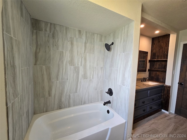 bathroom featuring vanity, a textured ceiling, and tiled shower / bath combo