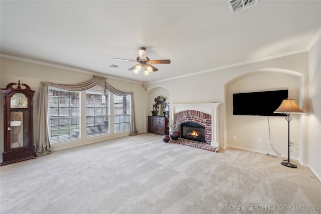 unfurnished living room featuring ornamental molding, a brick fireplace, ceiling fan, and light colored carpet