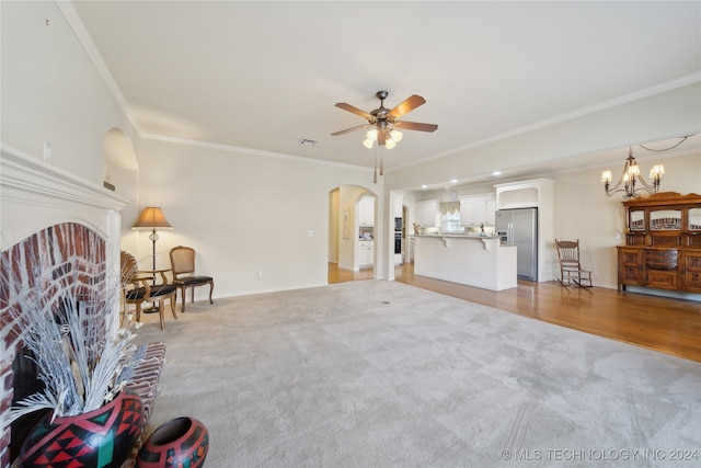 living room featuring ceiling fan with notable chandelier, a brick fireplace, light hardwood / wood-style flooring, and crown molding