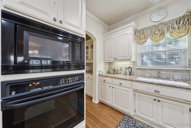 kitchen with white cabinets, sink, tasteful backsplash, black appliances, and light hardwood / wood-style floors