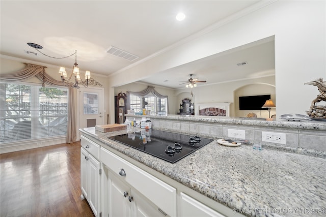 kitchen with black electric cooktop, dark hardwood / wood-style floors, ceiling fan with notable chandelier, white cabinets, and crown molding