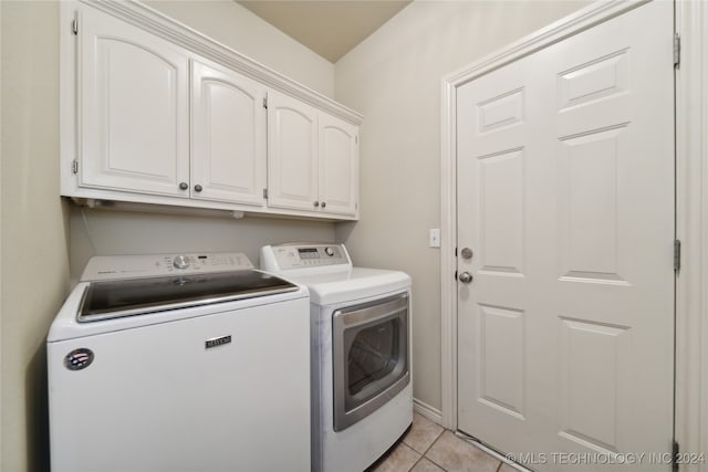 washroom featuring light tile patterned floors, washing machine and clothes dryer, and cabinets