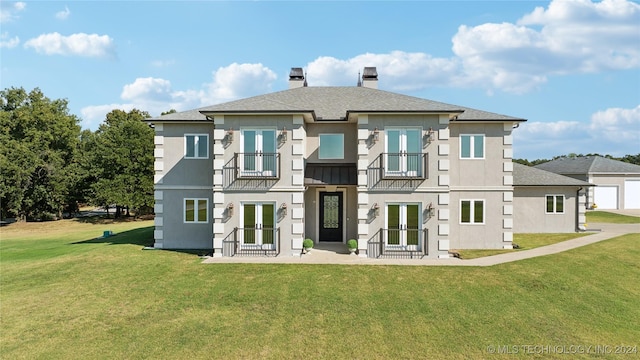 back of house with a balcony, a shingled roof, a yard, french doors, and a chimney