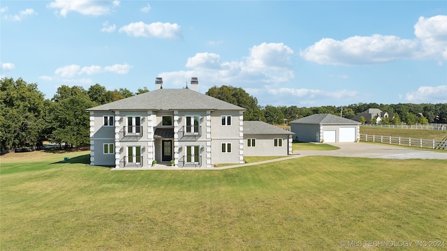 rear view of house featuring a lawn, a detached garage, an outbuilding, french doors, and stucco siding