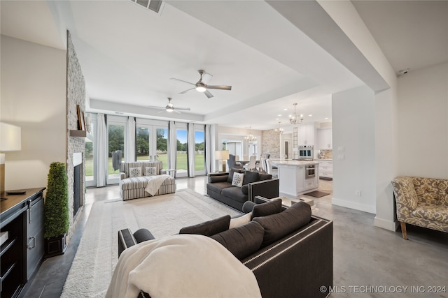 living area featuring baseboards, visible vents, a tray ceiling, concrete flooring, and a fireplace