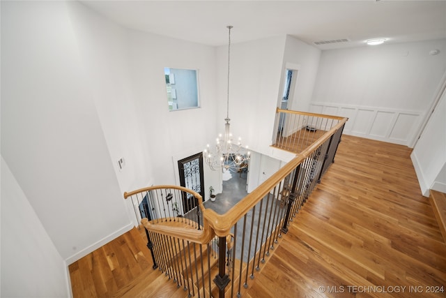 stairs featuring visible vents, a chandelier, wood finished floors, and a decorative wall