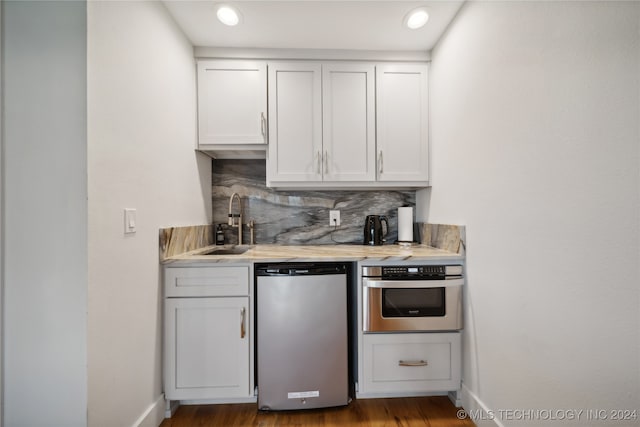 kitchen featuring light countertops, backsplash, stainless steel oven, a sink, and dishwashing machine