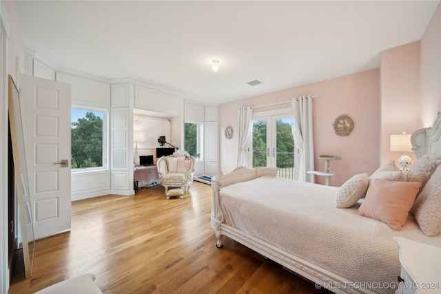 bedroom with light wood finished floors, visible vents, and french doors