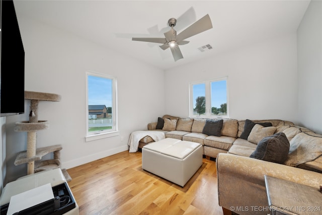 living area with light wood finished floors, a ceiling fan, visible vents, and baseboards