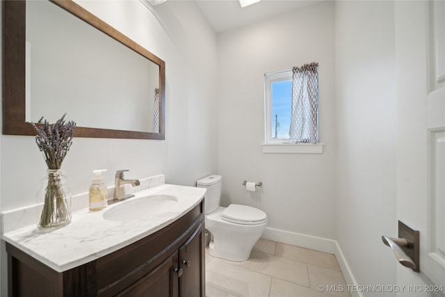 bathroom featuring tile patterned flooring, baseboards, vanity, and toilet