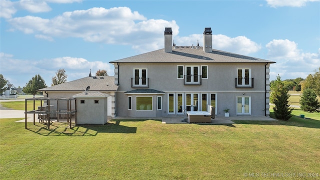 rear view of house featuring a patio area, a yard, stucco siding, and french doors