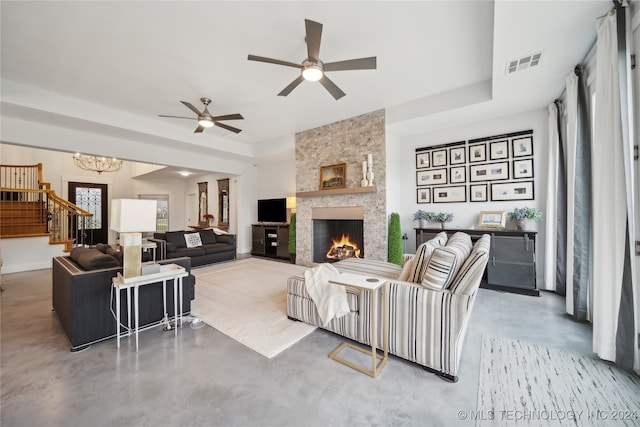 living room featuring a fireplace, visible vents, stairway, a tray ceiling, and finished concrete floors