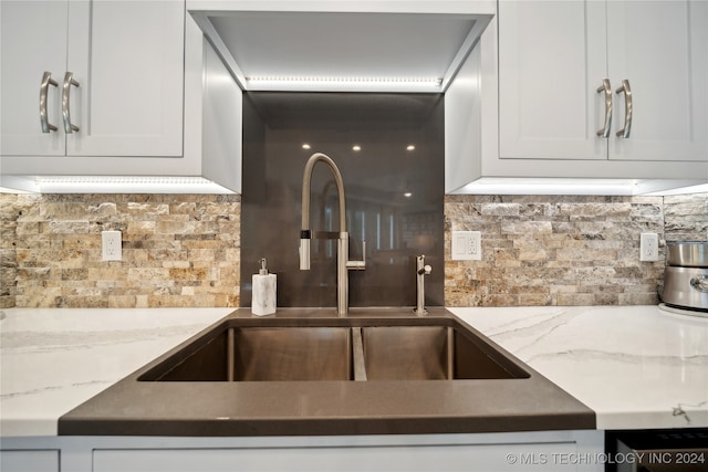 kitchen with tasteful backsplash, light stone counters, and white cabinets