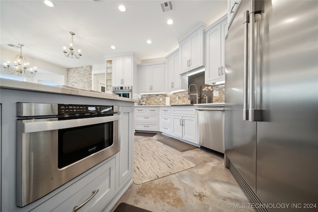 kitchen with a sink, visible vents, white cabinets, appliances with stainless steel finishes, and backsplash