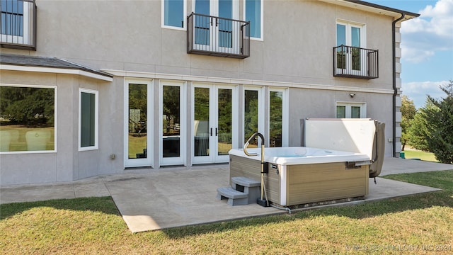 rear view of property featuring french doors, a hot tub, and stucco siding