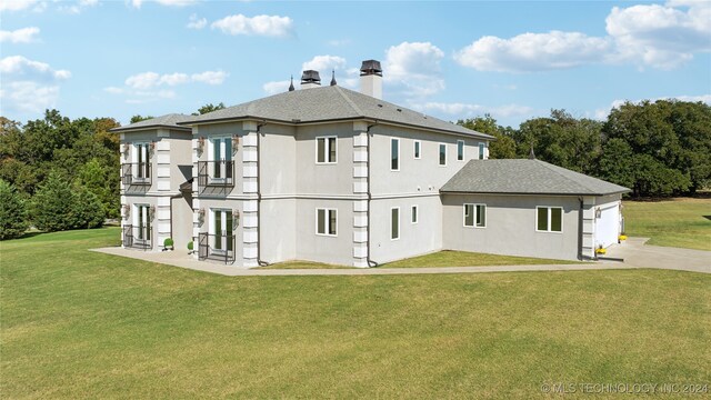 rear view of house featuring a garage, driveway, a chimney, a yard, and french doors