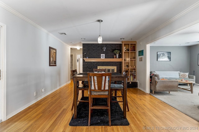 dining room featuring ornamental molding, light hardwood / wood-style flooring, and a brick fireplace