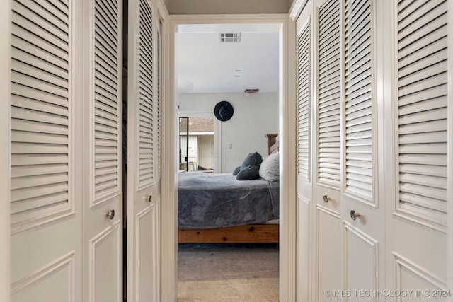 bedroom featuring light carpet and multiple closets