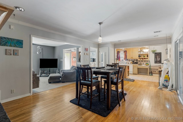 dining space with crown molding and light wood-type flooring