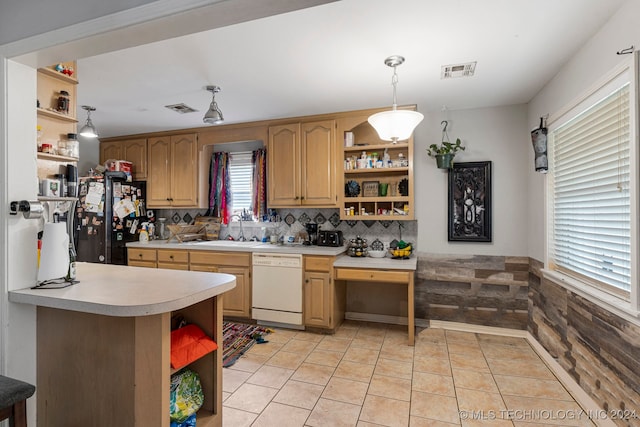 kitchen with tasteful backsplash, sink, white dishwasher, black fridge, and pendant lighting