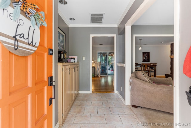 entryway with ornamental molding and light tile patterned floors