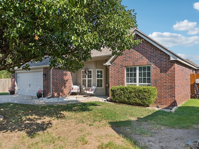 view of front of house featuring a front yard, a garage, and a patio