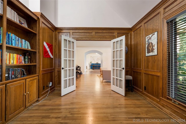 interior space with light hardwood / wood-style floors, french doors, wooden walls, and built in features