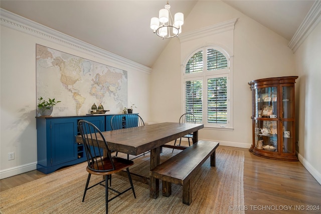 dining room featuring lofted ceiling, ornamental molding, light wood-type flooring, and a notable chandelier