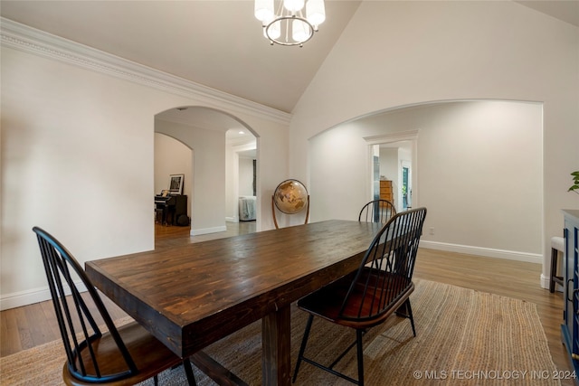 dining room featuring high vaulted ceiling, ornamental molding, a chandelier, and hardwood / wood-style floors