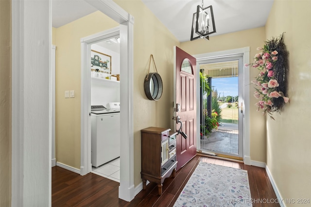 foyer entrance featuring dark hardwood / wood-style flooring, washing machine and clothes dryer, and a chandelier