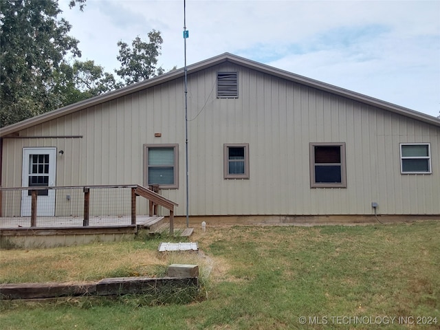 rear view of house with a wooden deck and a lawn