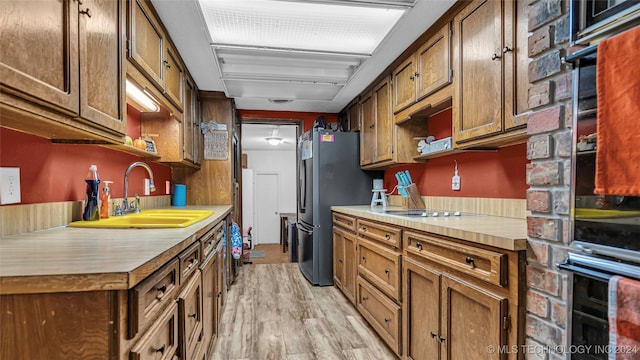 kitchen with appliances with stainless steel finishes, light hardwood / wood-style floors, and sink