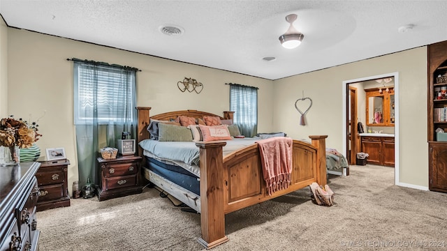 carpeted bedroom featuring a textured ceiling and ensuite bath