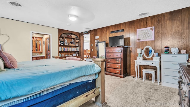 carpeted bedroom featuring wood walls, a textured ceiling, and ensuite bath