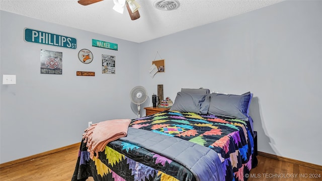 bedroom with a textured ceiling, hardwood / wood-style floors, and ceiling fan