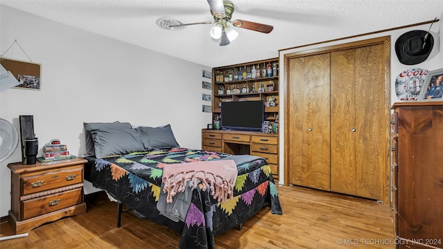 bedroom with ceiling fan, a textured ceiling, light hardwood / wood-style flooring, and a closet