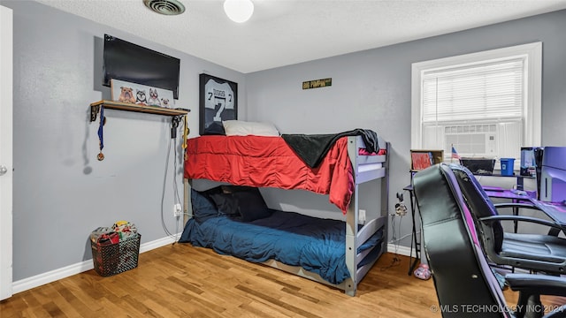 bedroom with a textured ceiling and hardwood / wood-style flooring