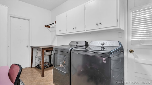 clothes washing area featuring washing machine and dryer and cabinets