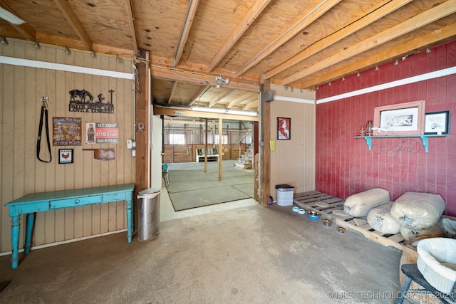 misc room with concrete flooring and wooden walls