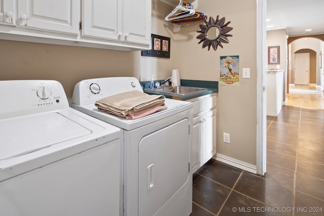 clothes washing area with washer and dryer, sink, cabinets, and dark tile patterned floors