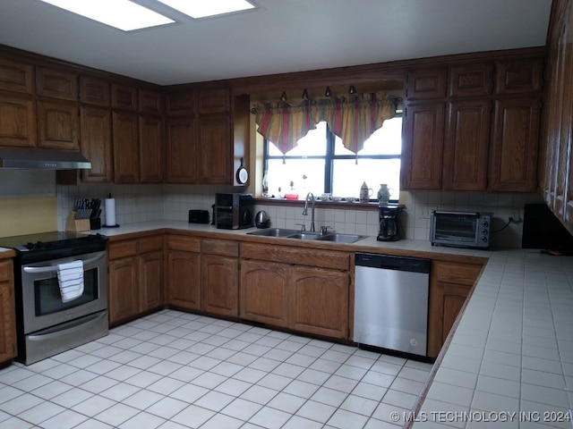 kitchen with decorative backsplash, stainless steel appliances, tile counters, and sink